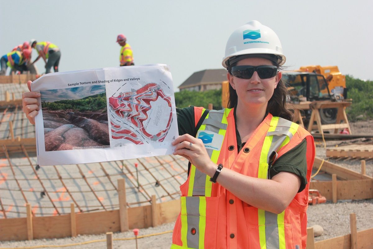 A wiman hlding an explanation paper with a map on a construction site