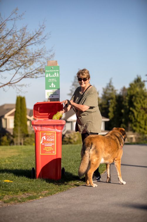 Une femme qui jette les excréments de son chien dans une poubelle faite pour cet usage.