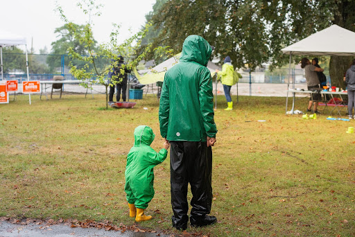 A man and a toddler going for a walk in a park under the rain